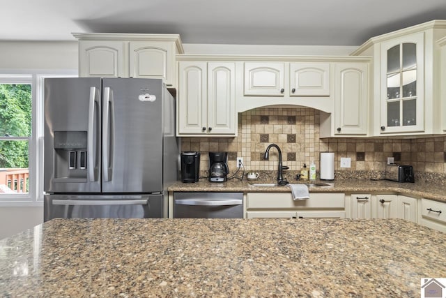 kitchen with decorative backsplash, stainless steel appliances, dark stone counters, and sink