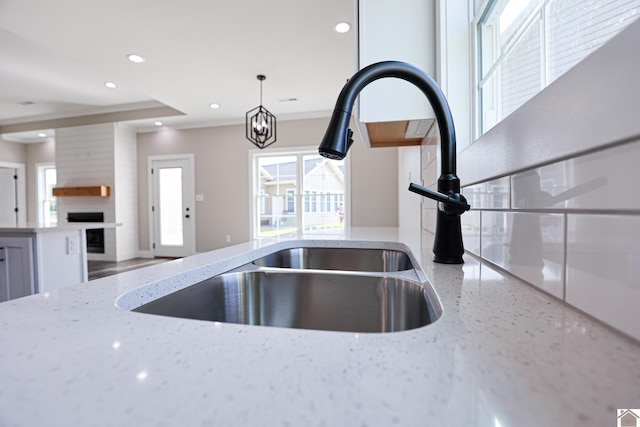 details with a sink, light stone countertops, a large fireplace, decorative light fixtures, and recessed lighting