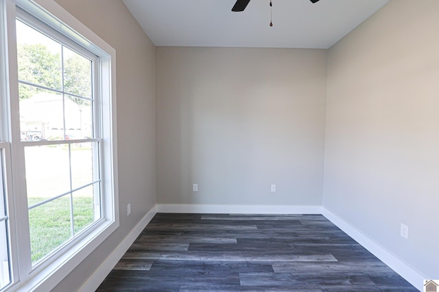empty room with baseboards, ceiling fan, and dark wood finished floors