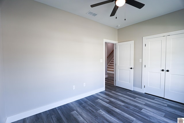 unfurnished bedroom featuring baseboards, a closet, visible vents, and dark wood-type flooring