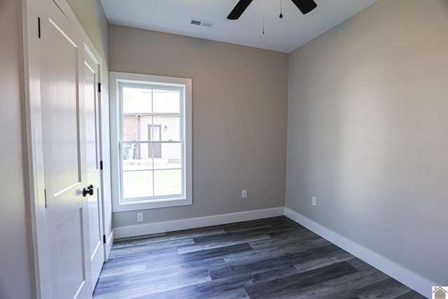 empty room with baseboards, ceiling fan, visible vents, and dark wood finished floors