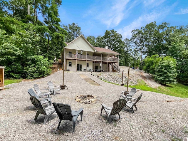 back of house featuring an outdoor fire pit, a wooden deck, and a patio