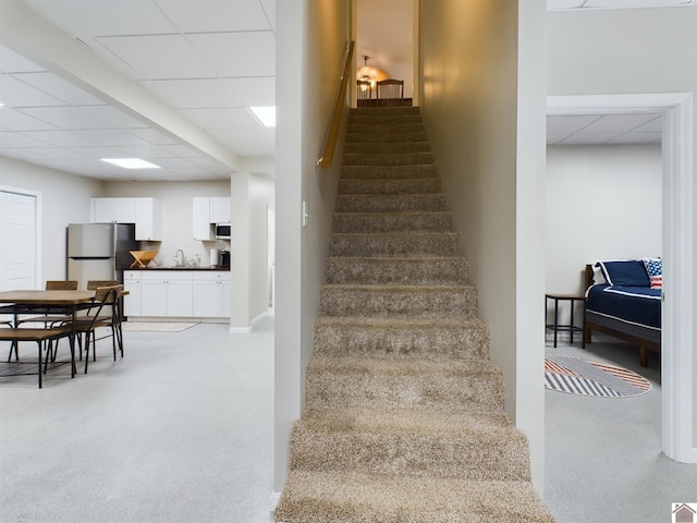 stairway featuring sink, carpet, and a paneled ceiling