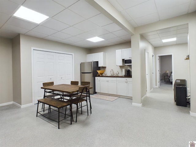 dining area with sink, light carpet, and a drop ceiling