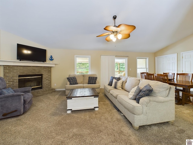 living room featuring carpet, a brick fireplace, vaulted ceiling, and ceiling fan