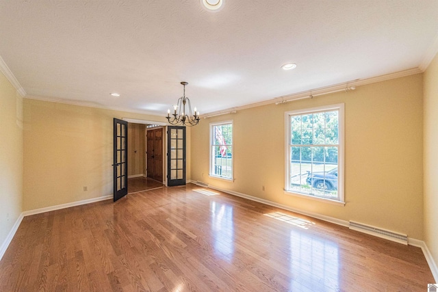 spare room with french doors, hardwood / wood-style flooring, an inviting chandelier, and crown molding