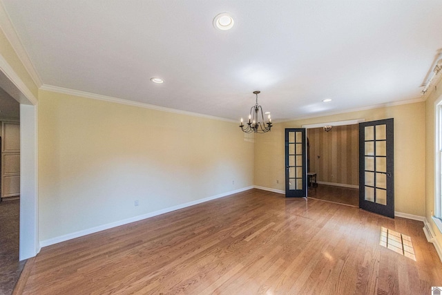 unfurnished room with a notable chandelier, wood-type flooring, crown molding, and french doors