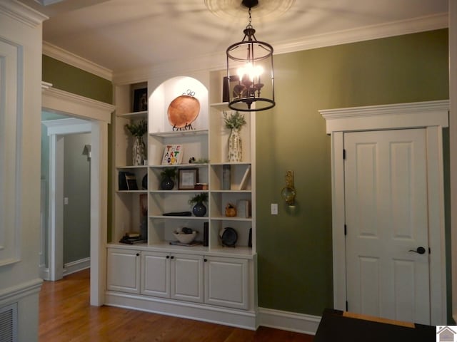 unfurnished dining area with a chandelier, wood-type flooring, built in features, and ornamental molding