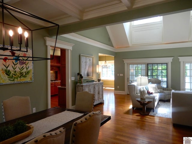 dining area with light wood-type flooring, an inviting chandelier, crown molding, and beamed ceiling