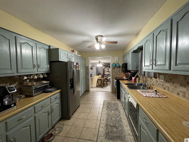 kitchen featuring ceiling fan, sink, stainless steel appliances, decorative backsplash, and light tile patterned flooring