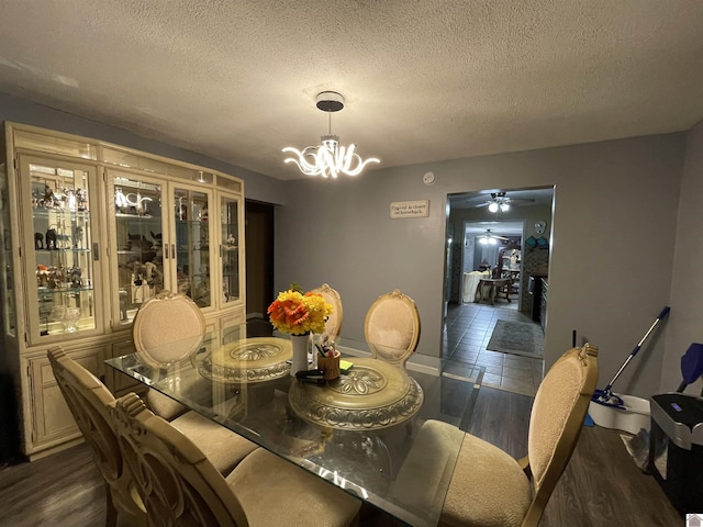 dining area featuring a notable chandelier, dark hardwood / wood-style flooring, and a textured ceiling