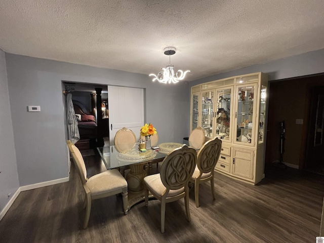 dining area featuring a textured ceiling, dark hardwood / wood-style flooring, and an inviting chandelier