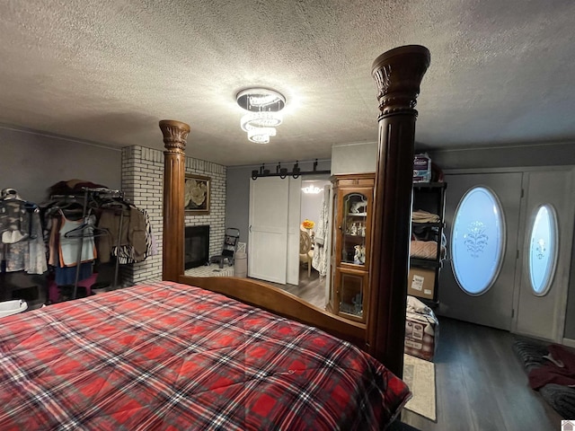 bedroom with a fireplace, wood-type flooring, and a textured ceiling