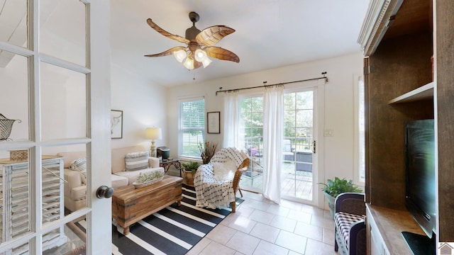 living area with light tile patterned floors and ceiling fan