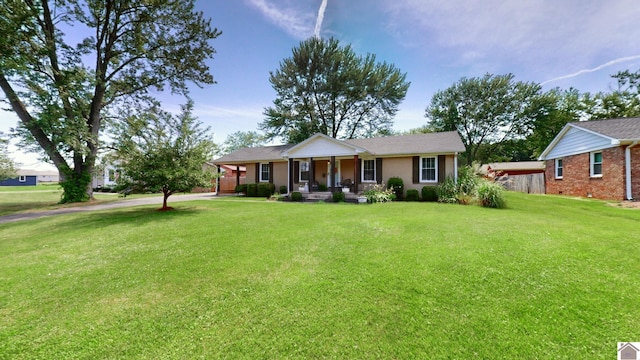 ranch-style home featuring covered porch and a front yard