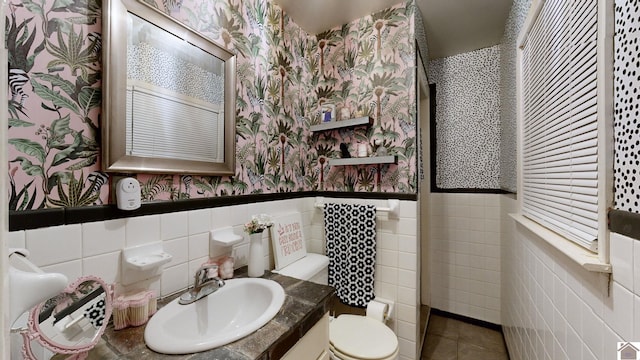 bathroom with tile patterned flooring, vanity, toilet, and tile walls