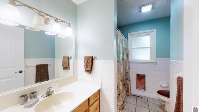 bathroom featuring vanity, a textured ceiling, tile walls, tile patterned flooring, and toilet