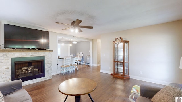 living room featuring ceiling fan, dark hardwood / wood-style flooring, and a brick fireplace