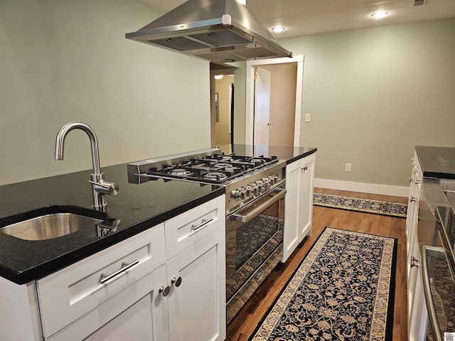 kitchen with white cabinetry, sink, dark wood-type flooring, island exhaust hood, and high end stainless steel range