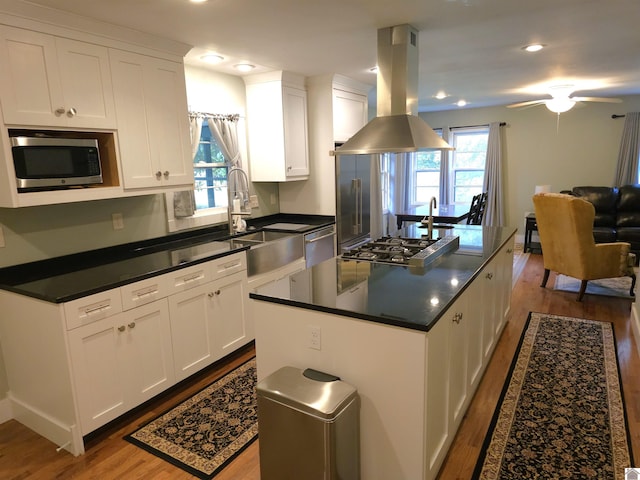 kitchen featuring white cabinets, sink, a kitchen island, island range hood, and stainless steel appliances