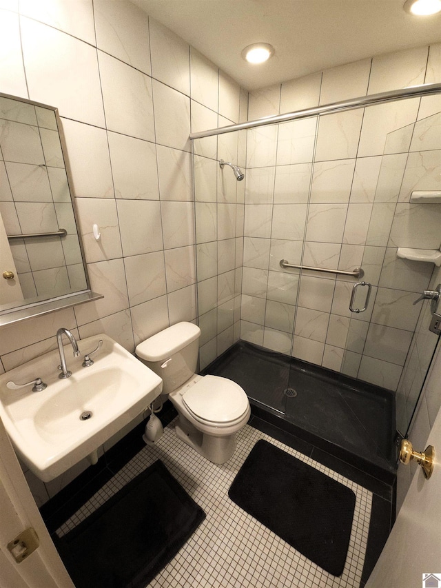 bathroom with sink, tile patterned floors, an enclosed shower, toilet, and tile walls