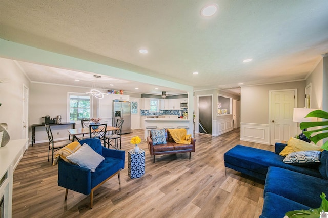 living room with crown molding, a textured ceiling, and light hardwood / wood-style floors