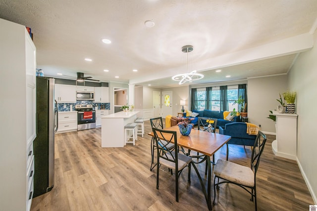 dining space with ceiling fan with notable chandelier and light wood-type flooring