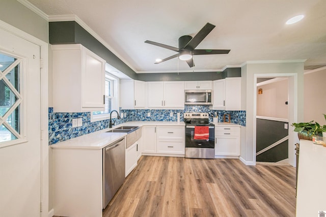 kitchen featuring sink, appliances with stainless steel finishes, tasteful backsplash, light hardwood / wood-style floors, and white cabinets