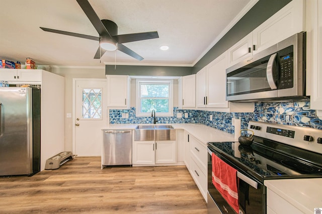 kitchen with appliances with stainless steel finishes, sink, white cabinets, backsplash, and crown molding