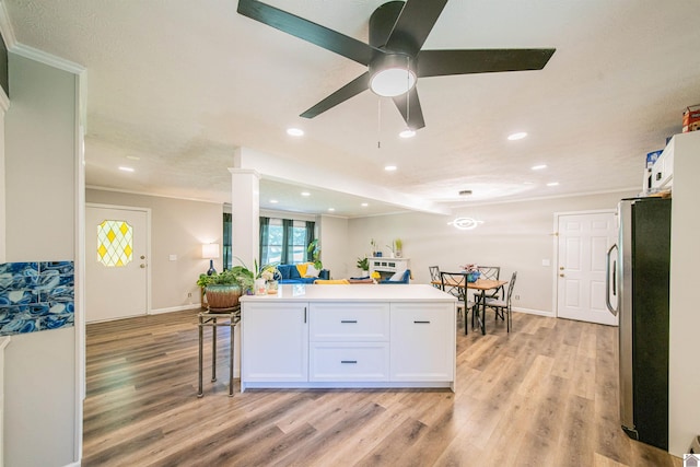 kitchen with crown molding, light hardwood / wood-style floors, stainless steel refrigerator, and white cabinets