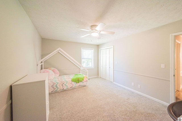 bedroom featuring ceiling fan, carpet flooring, a closet, and a textured ceiling