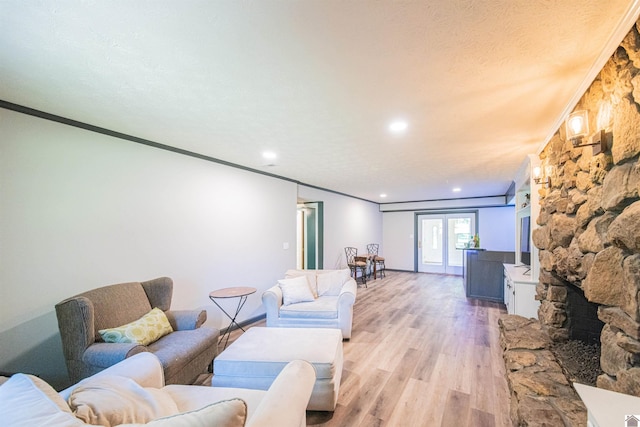 living room with ornamental molding, a textured ceiling, a fireplace, and light hardwood / wood-style flooring