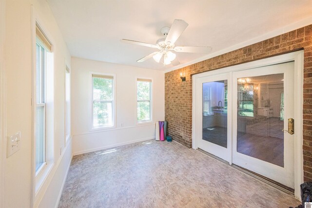 spare room with ceiling fan and brick wall