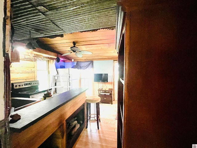 interior space with light tile patterned floors, stainless steel electric stove, ceiling fan, and white fridge