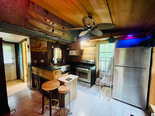 kitchen featuring ceiling fan, stainless steel appliances, light hardwood / wood-style floors, and wooden ceiling