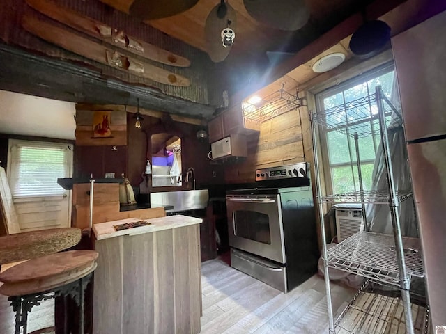 kitchen featuring light hardwood / wood-style floors, wooden walls, and stainless steel range with electric cooktop