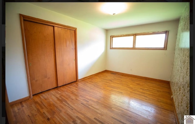 unfurnished bedroom with a closet and light hardwood / wood-style floors