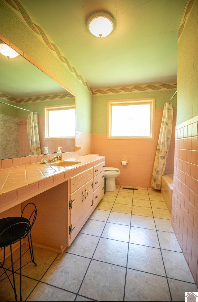 full bathroom with tile walls, toilet, a wealth of natural light, and vanity