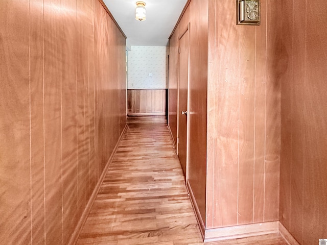 hallway with light hardwood / wood-style flooring and wooden walls