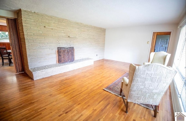 living room featuring a textured ceiling, a large fireplace, and hardwood / wood-style floors