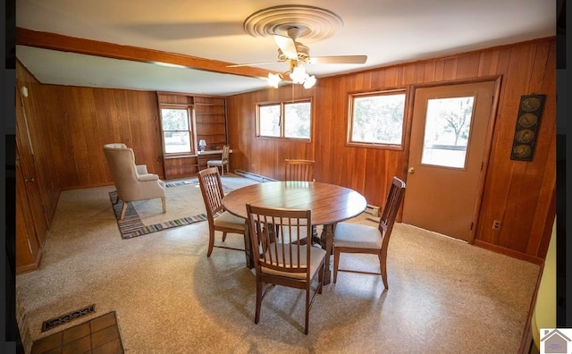 dining area featuring a baseboard heating unit, wood walls, and ceiling fan