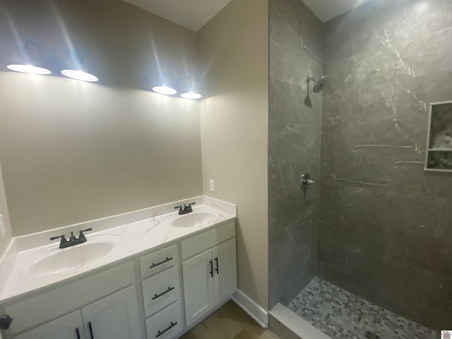 full bath with double vanity, a tile shower, and a sink