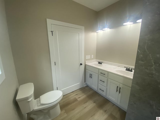 full bathroom with double vanity, toilet, a sink, and wood finished floors