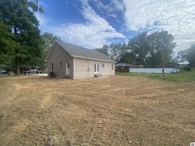 view of home's exterior with entry steps, central AC unit, and brick siding