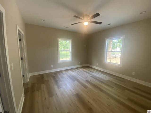 unfurnished room with light wood finished floors, a ceiling fan, visible vents, and baseboards