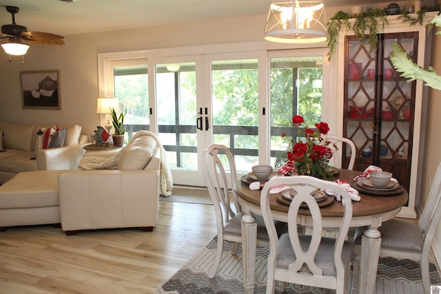 dining area with light wood-style floors, french doors, a healthy amount of sunlight, and a ceiling fan