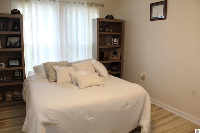 bedroom with multiple windows, baseboards, and wood finished floors