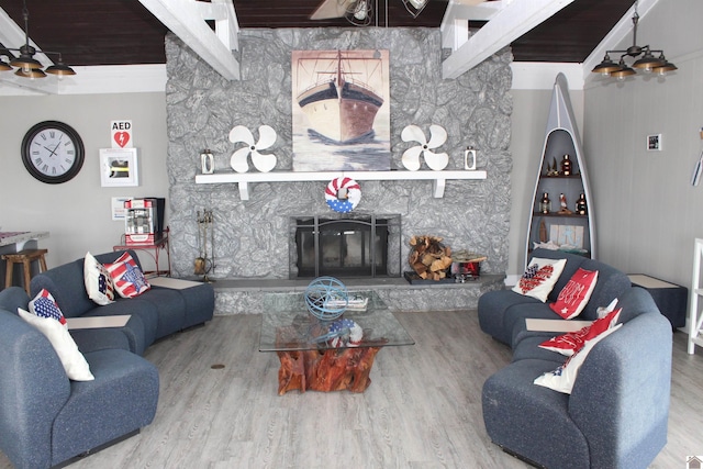 living room with beamed ceiling, a stone fireplace, and hardwood / wood-style flooring