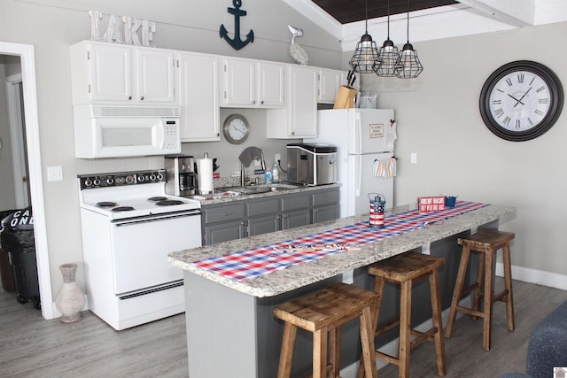 kitchen featuring white appliances, sink, white cabinetry, light hardwood / wood-style floors, and decorative light fixtures