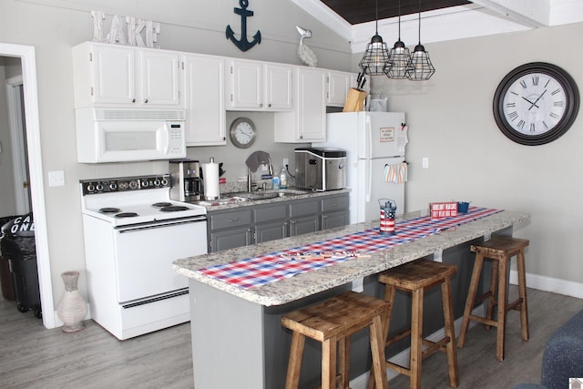 kitchen featuring white appliances, a breakfast bar area, a sink, and wood finished floors